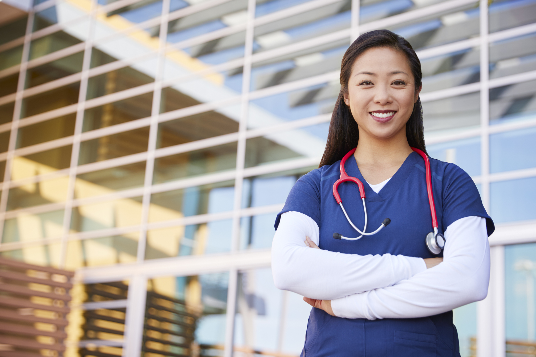 Medical worker smiling with crossed arms, a stethoscope hanging around neck